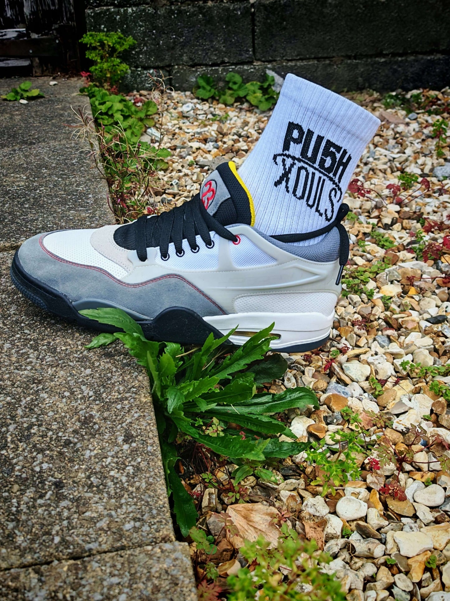 Crew Socks White worn with stylish sneakers on gravel, showcasing comfort and branding of PU5H XOULS.