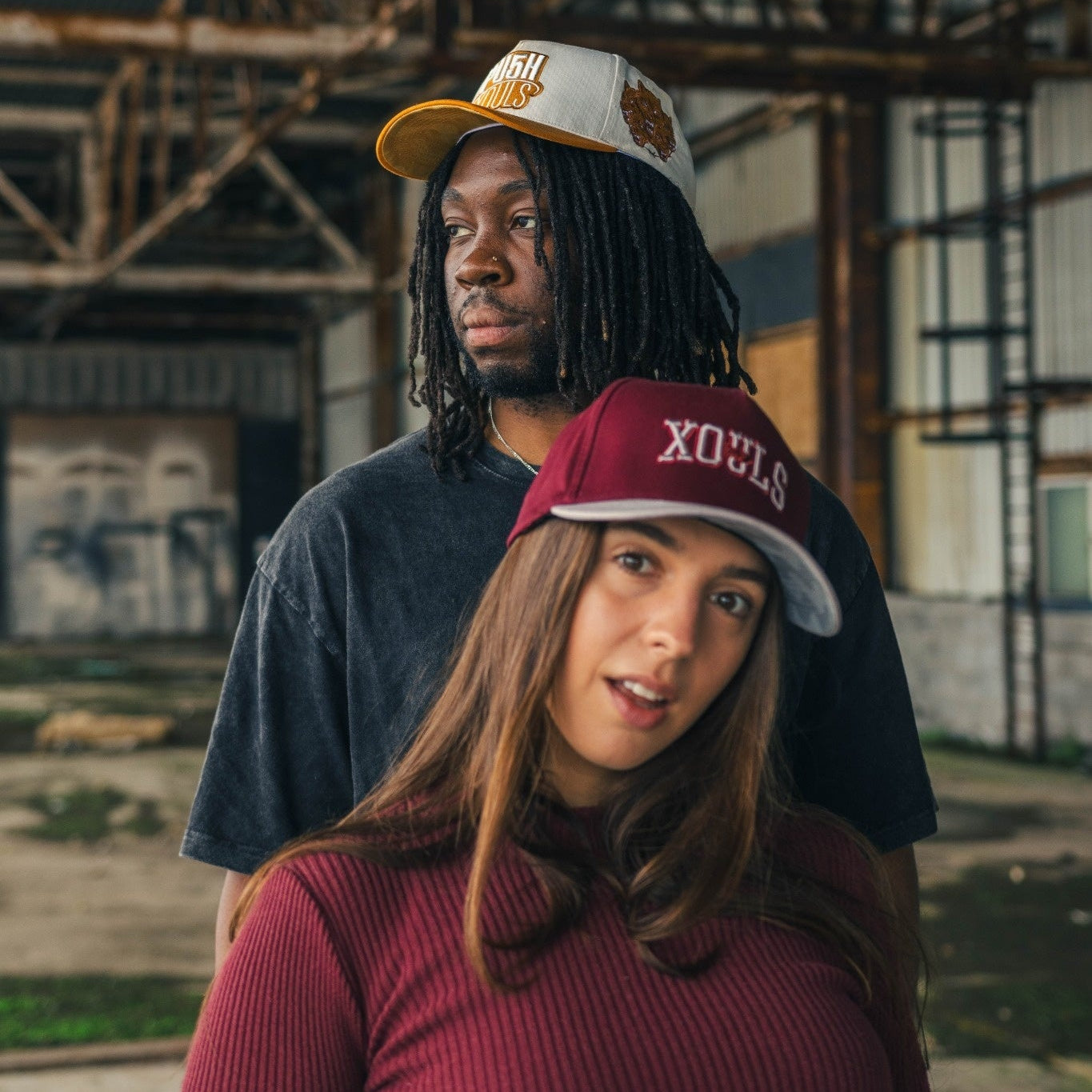 Two people wearing hats in an abandoned building setting